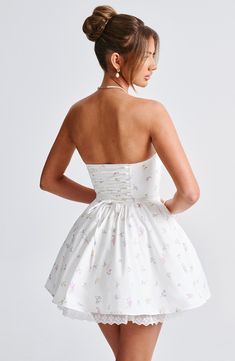 a woman in a short white dress with flowers on the skirt and backless top