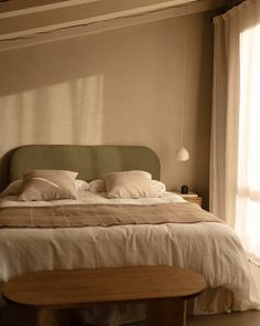 a large bed sitting in a bedroom next to a window with curtains on the windowsill