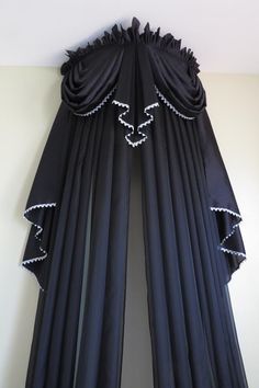 black drapes with beaded trim hang from the ceiling in front of a white wall