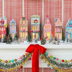 a christmas mantle with decorations and lights on it, including a red ribbon tied around the mantel