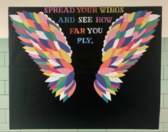 a poster with colorful wings on it in a classroom setting that reads spread your wings and see how far you fly