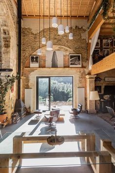 a living room filled with furniture and lots of windows next to a stone wall covered in pictures