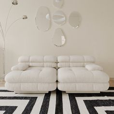 a white couch sitting on top of a black and white rug