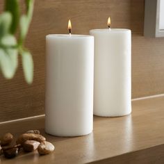 two white candles sitting on top of a counter