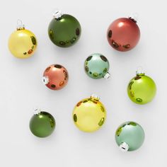 christmas ornaments are arranged on a white surface, including one green ornament and the other red