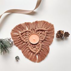 a candle that is sitting in the shape of a heart next to some pine cones