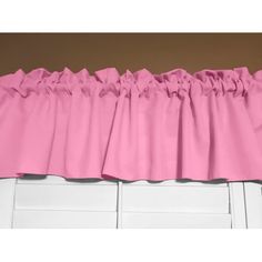 pink ruffled curtains hanging on the side of a window