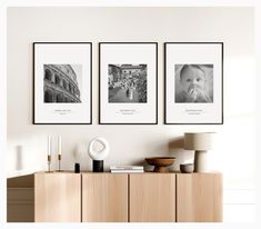 three black and white photographs hang on the wall next to a wooden cabinet in a living room