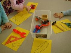 children sitting at a table with construction paper and scissors