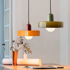 three lamps hanging from the ceiling above a table with flowers in vases on it