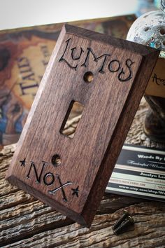 a wooden light switch cover with the words lumos and nox written on it