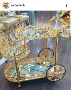 a gold serving cart with glass shelves and wheels on display in a store or restaurant