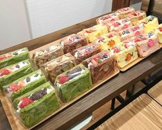 a table topped with lots of different types of cakes on top of wooden trays