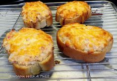 four pieces of bread sitting on top of a metal rack with cheese toppings in them