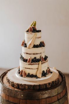 a three tiered cake with figs and blueberries on top