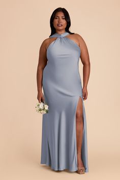 a woman in a blue dress with her legs slited up and holding a bouquet