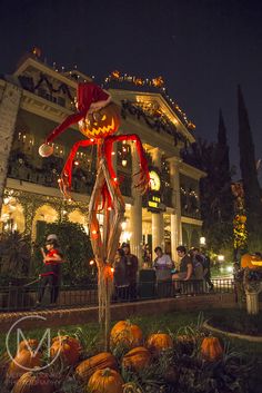 people are standing outside at night in front of a building with pumpkins on the ground