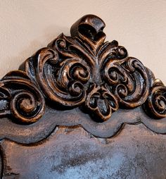 an ornately carved wooden headboard against a white wall