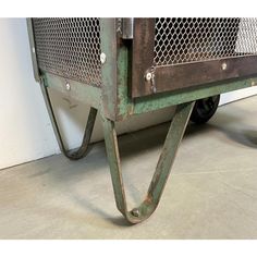 an old green metal cart sitting on the floor