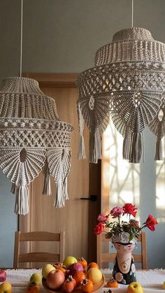 two chandeliers hanging from the ceiling above a table with fruit and flowers on it