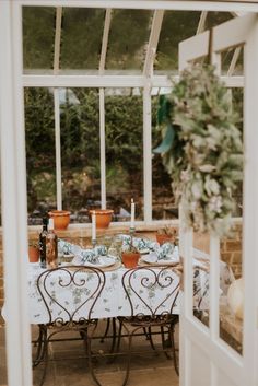 an outdoor table set for two with potted plants