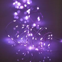 some purple lights that are on the ground in front of a white wall and black background