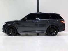 a grey range rover parked in a white room with black rims on the tires