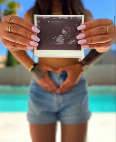 a woman holding an electronic device in her hands with the image of a baby on it's screen