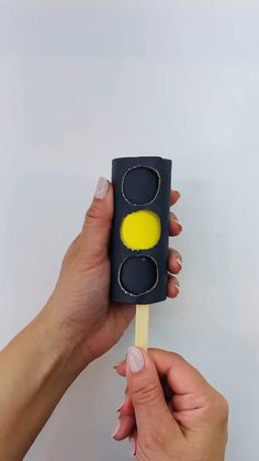 a hand holding a black and yellow traffic light lollipop