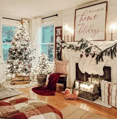 a living room decorated for christmas with stockings on the fire place and trees in pots