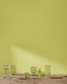 four glasses are sitting on a table in front of a yellow wall