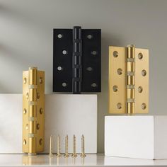 three different types of brass and black hinges on a white surface with two large, rectangular ones next to each other