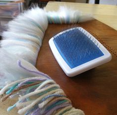 a blue and white brush sitting on top of a wooden table next to a pile of yarn