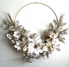 a wreath with flowers and leaves hanging on the wall in front of a white wall