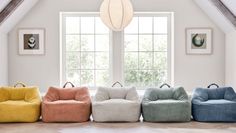 four different colored bean bags sitting on the floor in front of a window with two windows