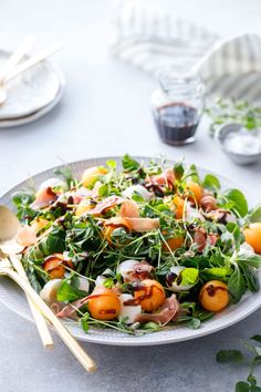 a white plate topped with salad next to silverware