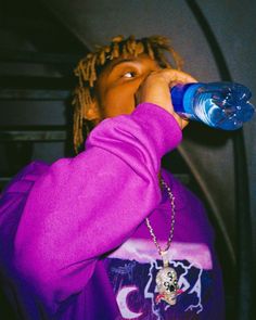 a young man drinking from a blue water bottle