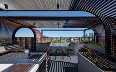 an outdoor dining area with wooden slatted roofing and benches on the side