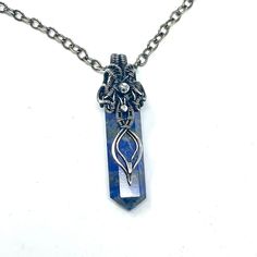 This pendant is handmade using fine silver wire wrapped around a Lapis Lazuli gemstone point. It hangs from an oval chain which closes with a hook clasp. The chain is 24 inches long ( 61 cm), the pendant is 6 cm long (2.4 inches) and 0.5 inches wide.It has been tarnished and polished to create an antique finish. Silver Hand Wrapped Metal Necklace, Wire Wrapped Amulet Pendant Crystal Necklace, Wire Wrapped Amulet Crystal Pendant Necklace, Spiritual Silver Crystal Necklace With Lobster Clasp, Spiritual Hand-wrapped Silver Necklaces, Spiritual Hand Wrapped Silver Necklace, Wire Wrapped Crystal Pendant Necklace In Metal, Sterling Silver Wire Wrapped Pendant Crystal Necklaces, Sterling Silver Wire Wrapped Pendant Crystal Necklace