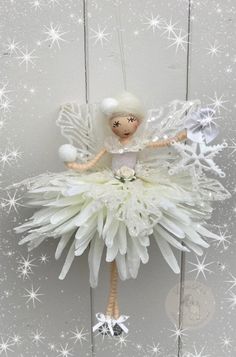 a white christmas angel ornament hanging from a string with snowflakes on it