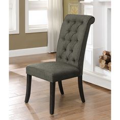 a gray chair sitting on top of a hard wood floor next to a fire place