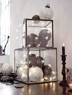 three glass boxes filled with ornaments on top of a wooden floor next to a window