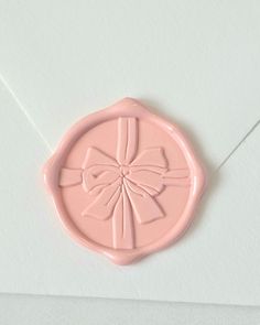 a pink wax stamp with a bow on it