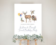 an animal themed birthday party sign on a easel with balloons and greenery around it