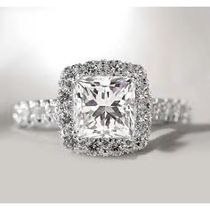 an engagement ring with a princess cut diamond surrounded by round brilliant pave and halos