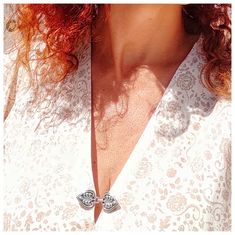 a woman with red hair is wearing a white shirt and has a silver necklace on her neck