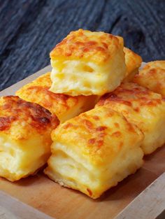 four cheesy biscuits sitting on top of a wooden cutting board