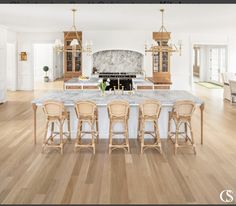 a large kitchen with an island in the middle and four chairs at the end, along with marble counter tops