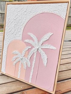 a pink and white card with palm trees in the background on a wooden bench outside