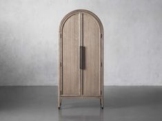 an arched wooden cabinet in the middle of a room with concrete walls and flooring